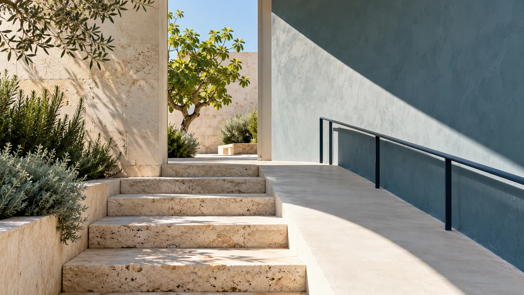 Fotografía arquitectónica de una rampa junto a escalones de piedra y un patio arbolado iluminado.